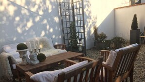A cozy outdoor seating area with a wooden table and chairs, surrounded by gravel. - Majestic Apartment in Brakel (Brakel)