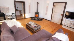 A cozy living room with a large sofa, a television, a fireplace, and a bookshelf. - Majestic Apartment in Brakel (Brakel)