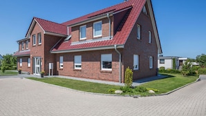 A two-story brick house with a red-tiled roof, a front entrance, and a paved driveway. - Albatros in the House of Aquarius (Rerik)