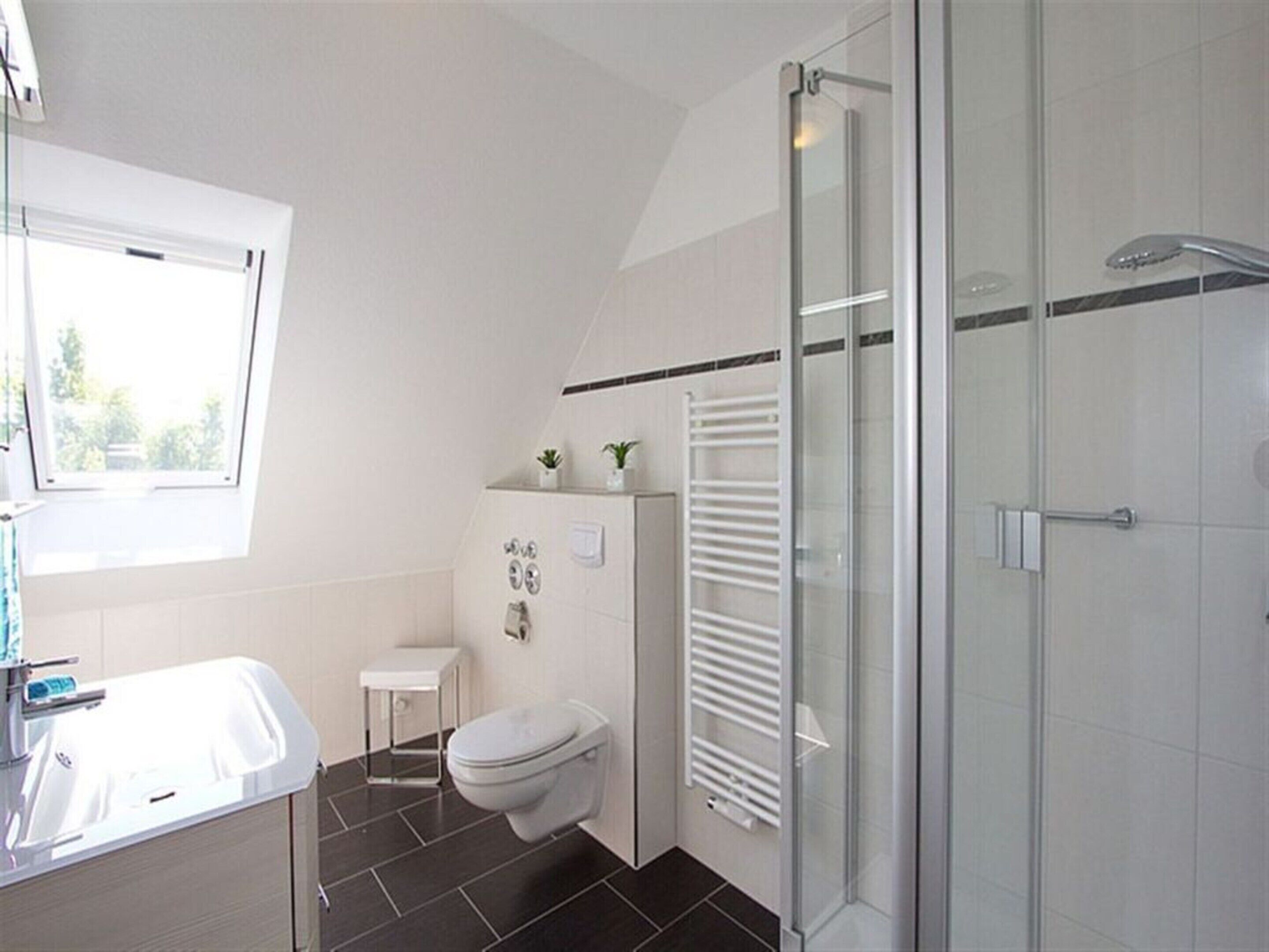 A modern bathroom with a shower, toilet, and sink.