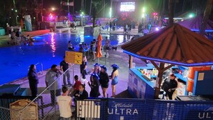 A nighttime pool area with people around the pool, a bar, and a tent structure. - In Entertainment District - Ample Bedding - Pool (South Padre Island)
