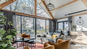A modern living room with a large window, a sofa, two armchairs, a dining area, and a kitchen. - Beautiful House With air Conditioning (Baarle-Nassau)