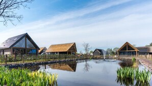 A tranquil lakeside setting with modern cabins, a clear sky, and a calm water body reflecting the structures. - Beautiful House With air Conditioning (Baarle-Nassau)