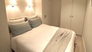Ein Schlafzimmer mit einem Bett, zwei Wandleuchten und einem Kleiderschrank.