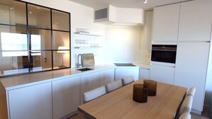 Eine moderne Küche mit weißen Schränken, einem Holzespeiseplatz und einem eingebauten Backofen.
