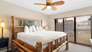 A rustic wooden bed with a headboard, a ceiling fan, and a view of the outside through large windows. - Shadow Ridge 112 | Walk to Lifts | Mountain Views | Kitchen | Fireplace | Pool & Hot Tub | Sauna (Park City)