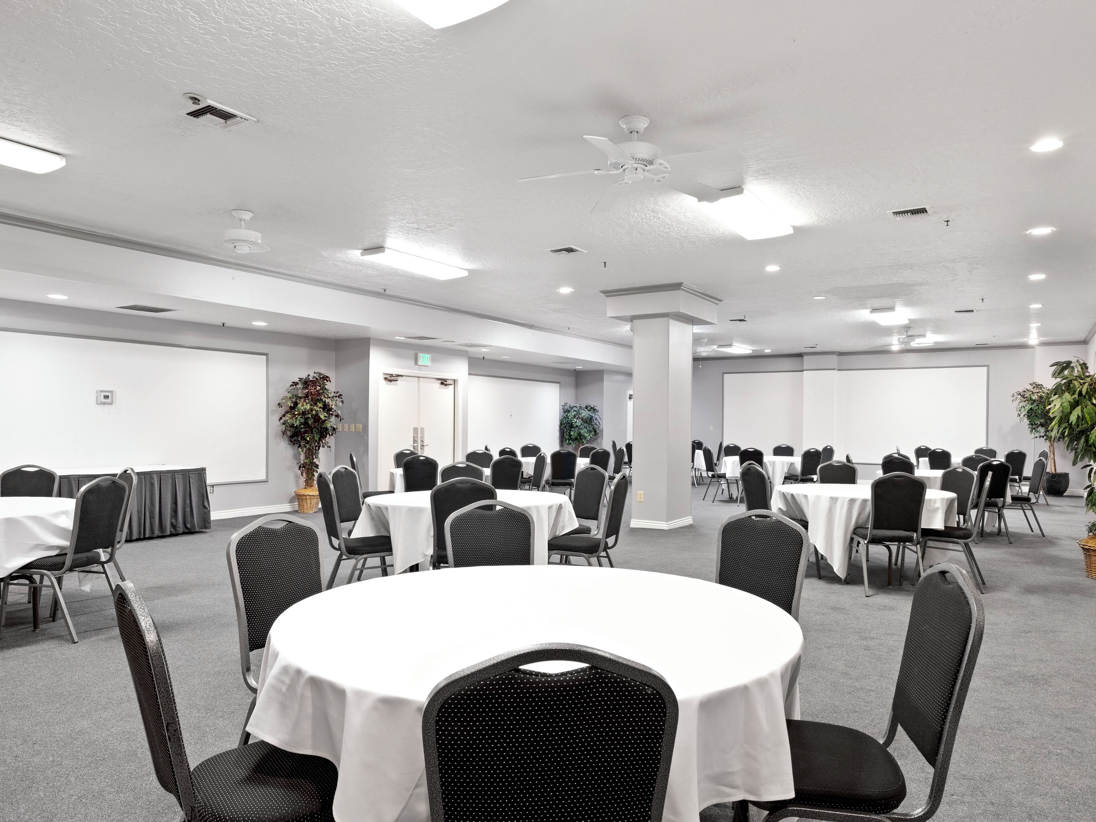 A conference room with round tables and chairs, white walls, and ceiling lights.