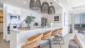 A modern kitchen with a central island, bar stools, and hanging pendant lights. - Wonderful 1 Bedroom condominium Encantame Verano 2103 (Puerto Peñasco)