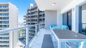 A balcony with a table and chairs, overlooking a cityscape and beach. - Las Palomas 3 BR 2 BA Topaz 801 (Puerto Peñasco)