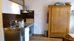 Eine kompakte Küche mit einer Edelstahl-Spüle, einem Holzschrank und einer kleinen Mülltonne.