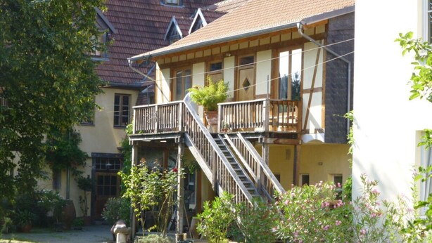 Ein traditionelles Gebäude im europäischen Stil mit einem Holzbalkon und einer Treppe, die zu der oberen Etage führt.