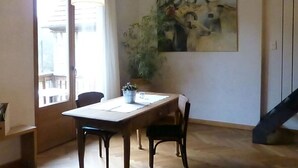 Ein Essbereich mit Holztisch und -stühlen, einem Blumentopf und einem Gemälde an der Wand.