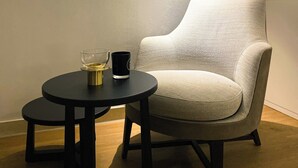 A room with a single armchair and a small round table with a glass and a black mug. - Apartment in Nieuwpoort Near the Beach (Nieuwpoort)