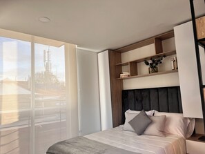 Ein modernes Schlafzimmer mit einem großen Bett, eingebauten Regalen und Blick auf eine Stadtlandschaft durch ein großes Fenster.