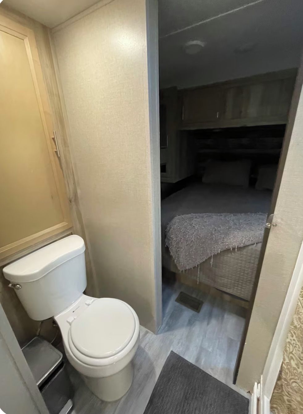 A compact bathroom with a toilet, a small trash bin, and a shower area.