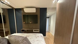 A bedroom with a bed, a television mounted on the wall, and a wardrobe. - Casa de Luxo, com Piscina na Penha, ZL. Aceita day use até 30 Pessoas (Jardim Popular São Paulo)