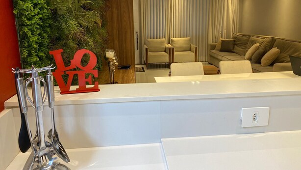 A modern living room with a white reception desk, a green wall with a 'LOVE' sign, and a sofa set. - Casa de Luxo, com Piscina na Penha, ZL. Aceita day use até 30 Pessoas (Jardim Popular São Paulo)
