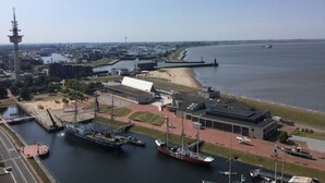 A harbor with ships docked, a lighthouse, and a large building labeled 'WÄNDEL'.