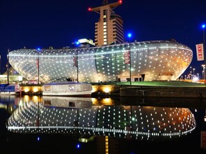 Un edificio grande y moderno con fachada de vidrio curvo y numerosas luces.