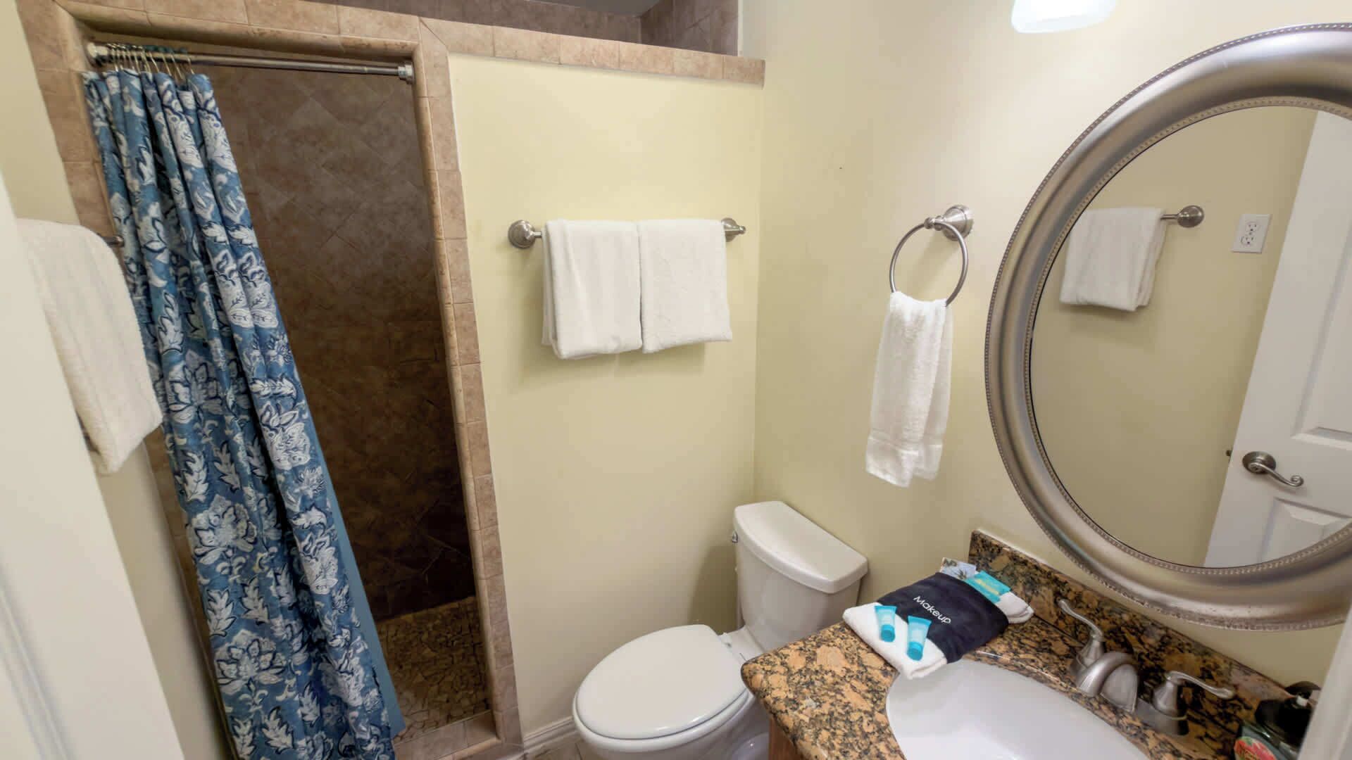 Une salle de bain équipée d’une douche, de toilettes, d’un lavabo et d’un grand miroir.