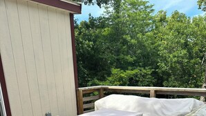 A wooden deck with covered outdoor seating and a building in the background. - Come stay at the quite and Cozy 
Rustic Hideaway  (Edwards)