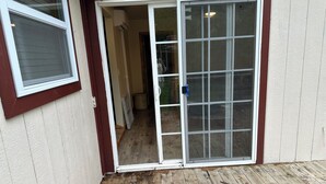 A wooden deck with a sliding glass door leading to a covered entryway. - Come stay at the quite and Cozy 
Rustic Hideaway  (Edwards)