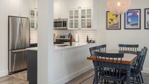 A modern kitchen with white cabinetry, stainless steel appliances, and a central island with seating.
