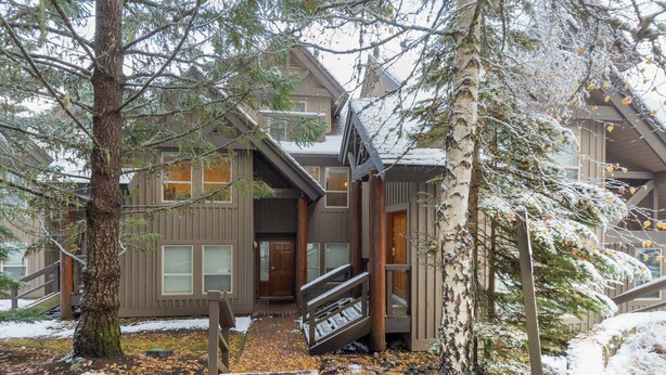 A two-story lodge with a wooden exterior, a covered entrance, and a staircase leading to the main entrance.