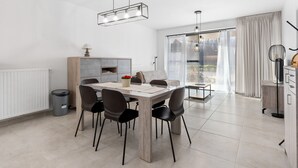 Uma sala de jantar moderna com uma mesa retangular, seis cadeiras e iluminação pendente.