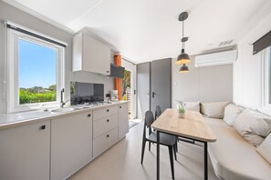 Uma cozinha moderna com uma janela ampla, uma área de refeições com uma mesa de madeira e um sofá.
