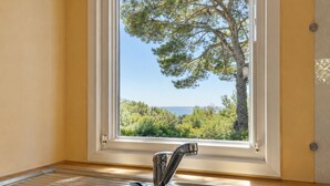 A kitchen with a stainless steel sink, a window with a view of a tree and the sea. - Le Romarin, mobile home with sea view (Hyères)