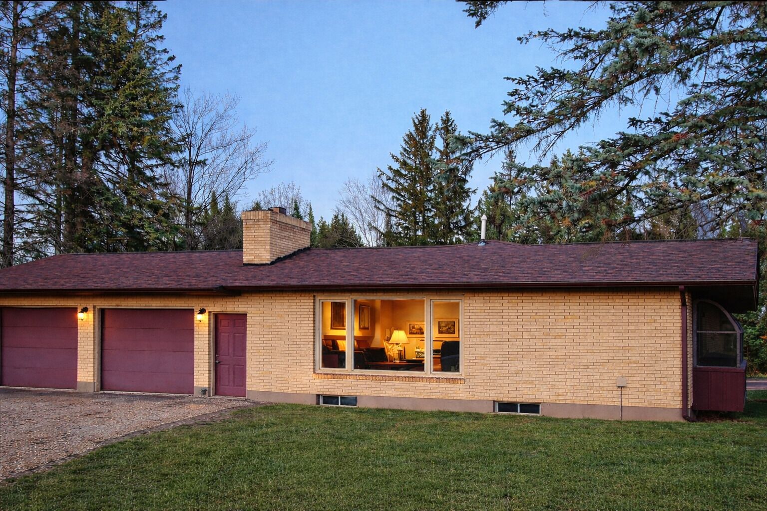 A single-story house with a garage, a front porch, and a window overlooking the yard.