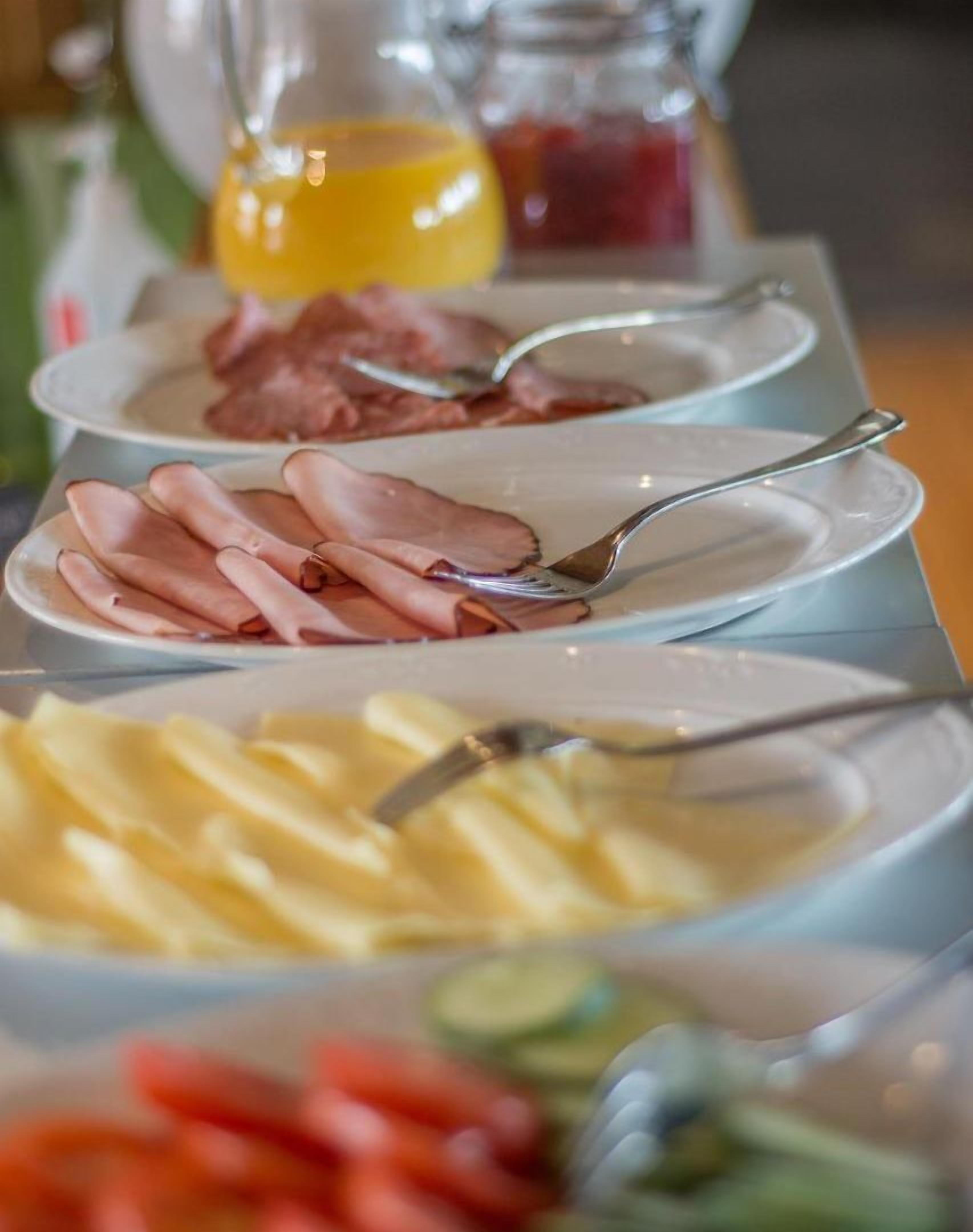 Un bufé con diferentes opciones de comida, incluyendo fiambres, queso y verduras.
