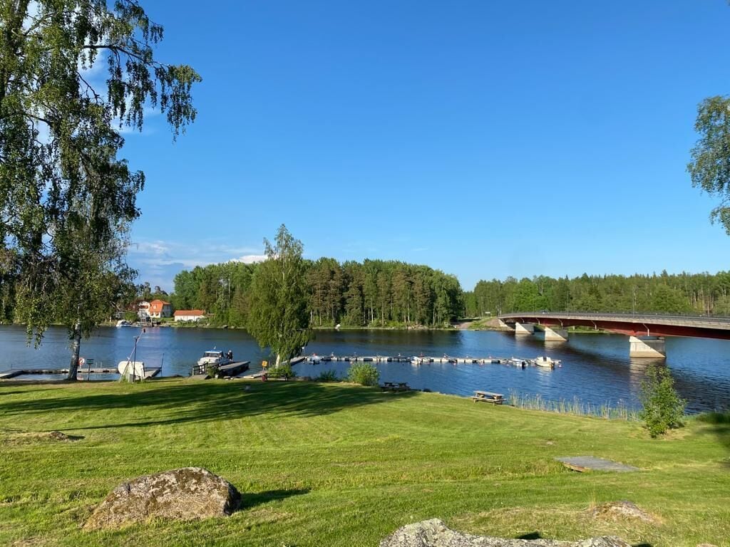 En vy över en sjö med ett brofäste, båtar och ett grönområde.