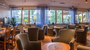 A hotel lobby with a seating area, large windows, and a television. - Lungsunds hotell & camping (Storfors)