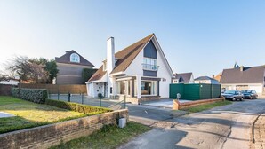 A residential street with houses, a green gate, and a parked car. - Villa in Koksijde Near the Sea (Koksijde)