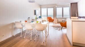 Une pièce moderne et bien éclairée, comprenant une table à manger, des chaises et un coin cuisine.