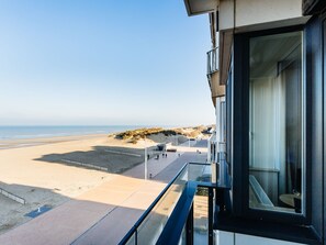 Un edifici modern amb un balcó que dona a una platja.