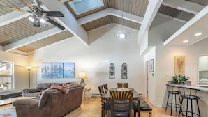 Ein geräumiges Loft mit hohen Decken, einem Essbereich, einem Wohnzimmer mit einer Couch und einer Küche mit Barhocker.
