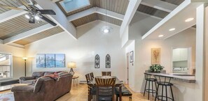 Ein geräumiges Loft mit hohen Decken, freiliegenden Balken, einem Essbereich und einer Küche mit Barhocker.