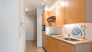 Uma cozinha moderna com armários de madeira, uma pia de aço inoxidável e um micro-ondas.