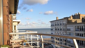 Uma varanda com vista para o mar e edifícios próximos.