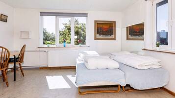 A bedroom with a bed, a chair, a window, and a radiator.