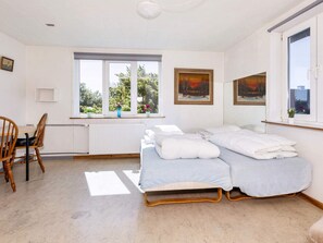 A bedroom with a bed, a chair, a window, and a radiator. - 12 Person Holiday Home in Roslev (Roslev)