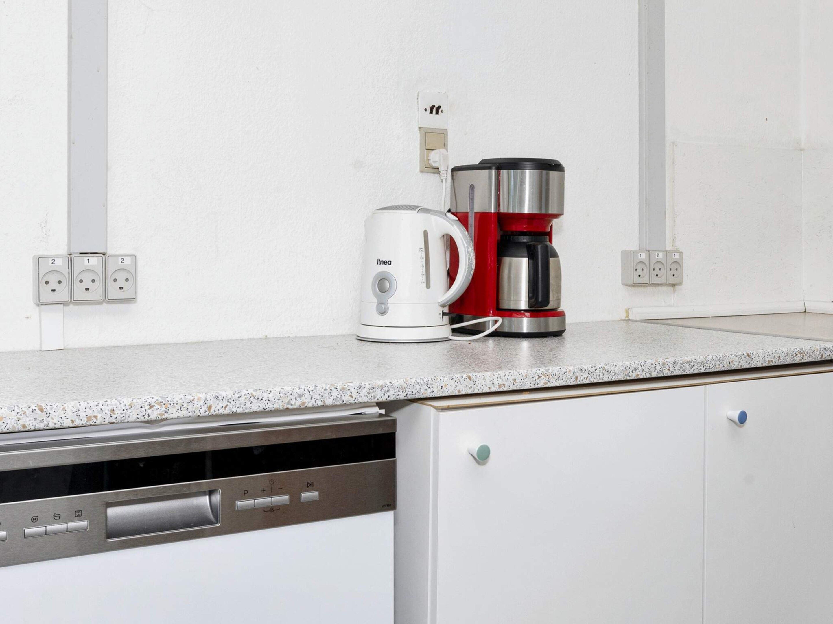 Una cocina equipada con cafetera, hervidor y lavavajillas.