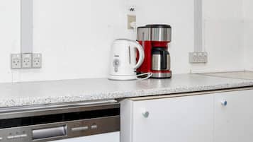 Una cocina equipada con cafetera, hervidor y lavavajillas.