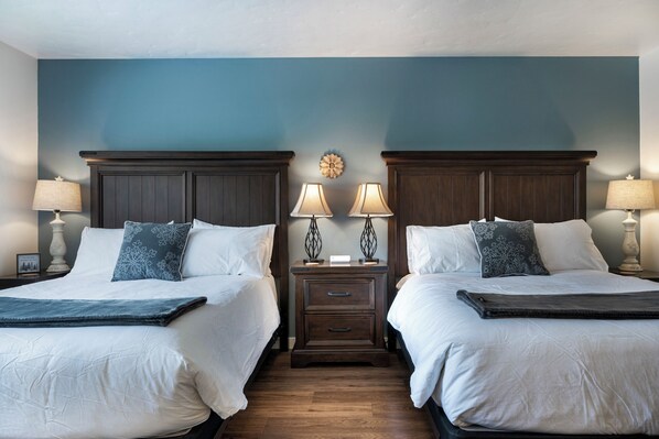 A hotel room with two beds, a nightstand with lamps, and a decorative wall piece. - At Flathead lake, 2 queens w/kitchenette - Marina Cay Huckleberry Suite (Bigfork)