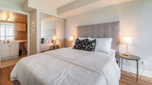 A modern bedroom with a large bed, a bedside table with a lamp, and a mirror cabinet. - Spacious 3bed/2 bath Downtown Toronto condo + Free Parking, min to CN tower (Toronto)