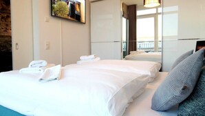Een hotelkamer met twee bedden, een grote spiegel en een aan de muur bevestigde televisie.