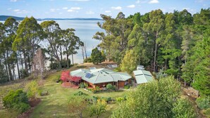 Une maison dotée d’un toit végétalisé, entourée d’arbres et bordée d’un lac.